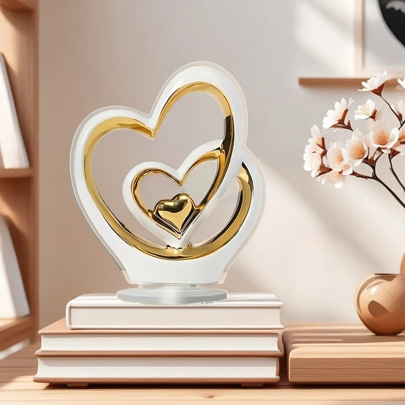 Minimalist heart-shaped ornament in white and gold ceramic, sitting on a stack of books.
