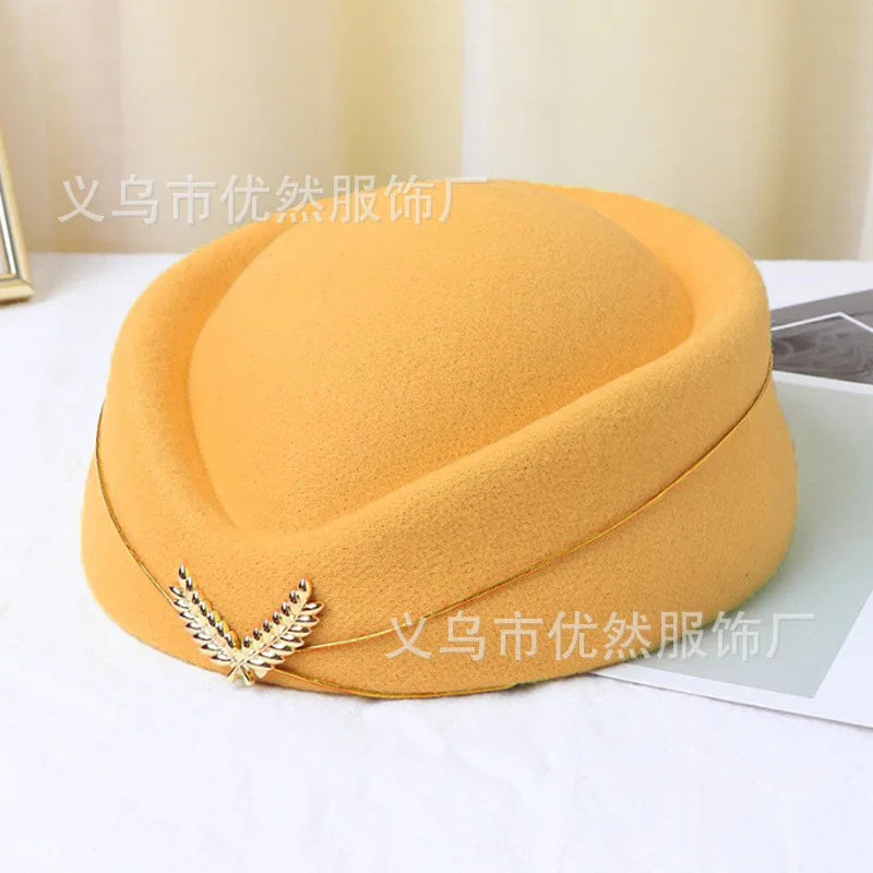 Yellow vintage-style stewardess pillbox hat, featuring a gold trim and an elegant metallic leaf brooch.