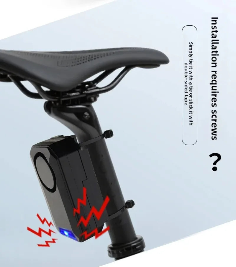 Black plastic bike alarm device attached to a seat post with cable ties, featuring an electronic siren component.