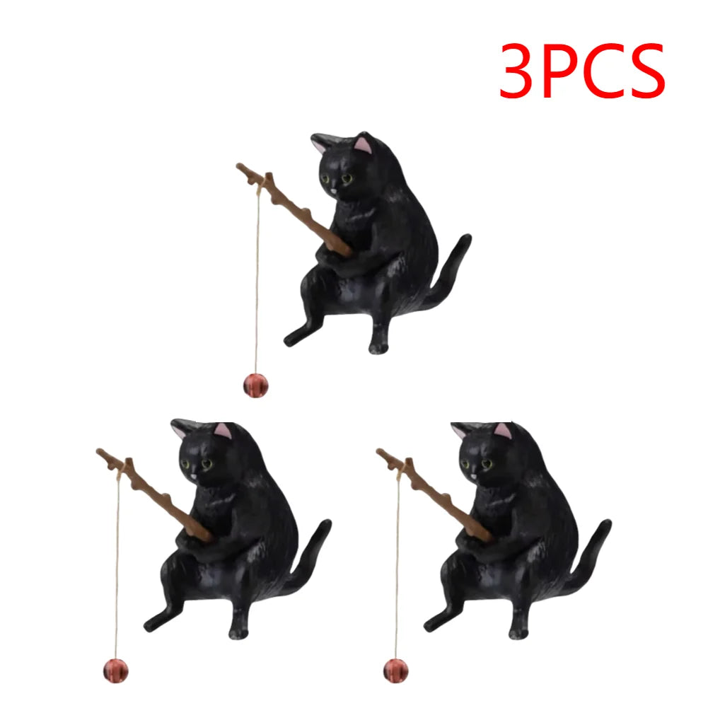 Set of three black cat aquarium ornaments, each modelled as a cat sitting and holding a small fishing rod with a bauble.
