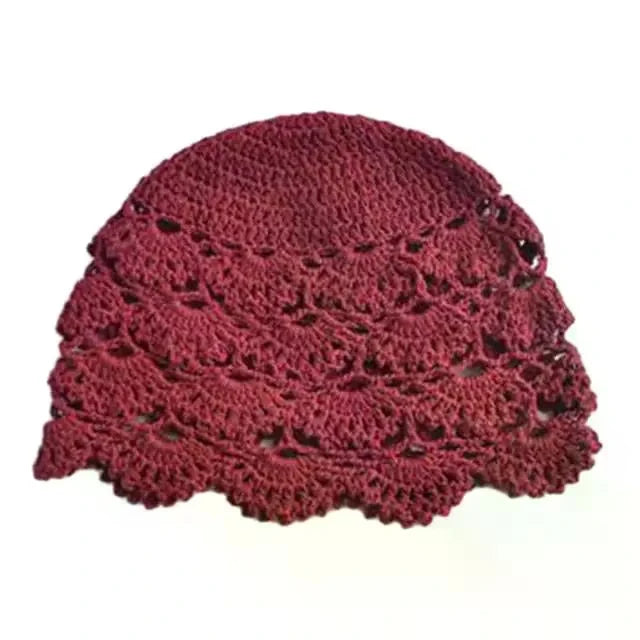 A burgundy women's beanie hat featuring intricate hollow crochet lace patterns and a scalloped edge.