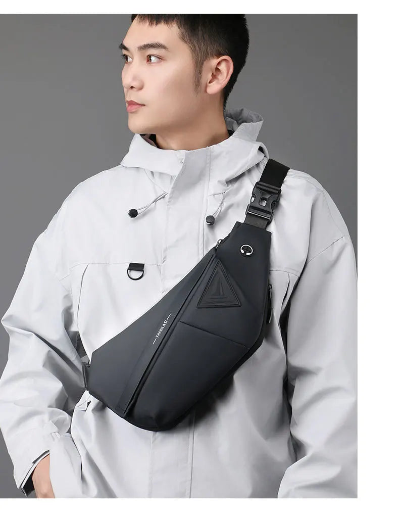 A man wearing a sleek, black anti-theft crossbody sling bag with a secure buckle strap and headphone port.