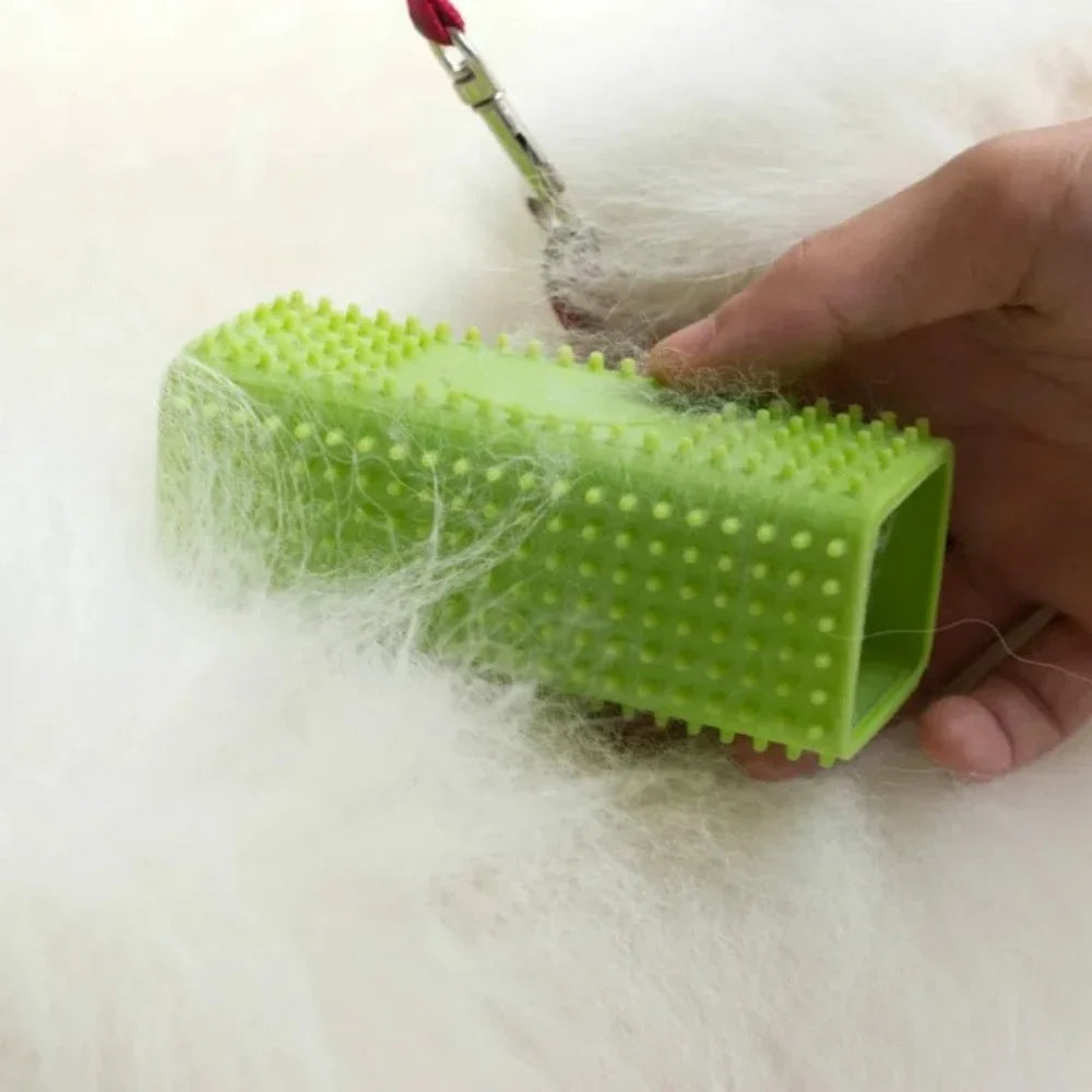 A lime green silicone pet hair removal brush held in a hand, covered in white pet fur.