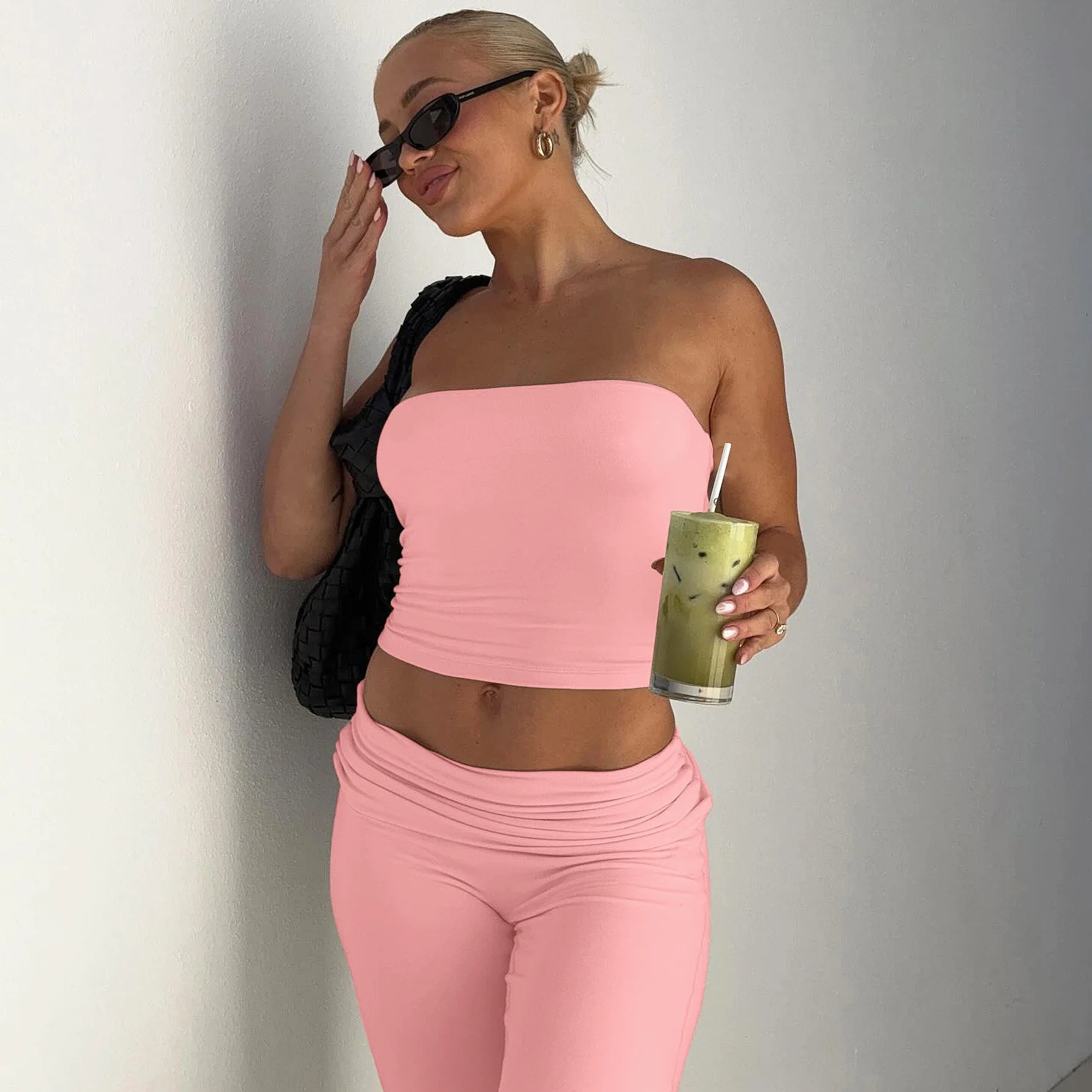 Woman wearing a baby pink strapless crop top and matching high-waisted leggings with a folded waistband.