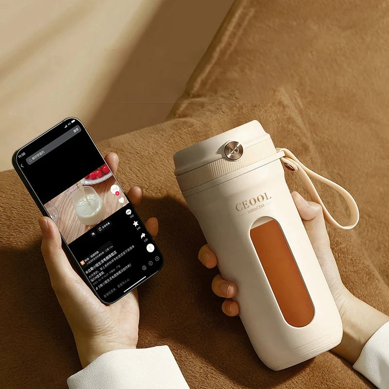 Cream-colored portable travel mug with a viewing window, locking lid, and carrying strap, held in hand.