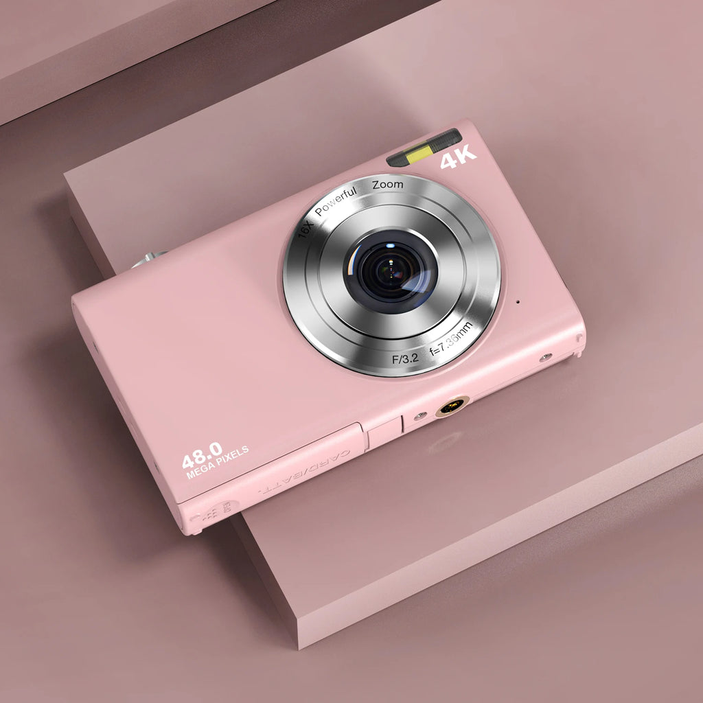 Pink plastic 48MP digital camera with 4K video capability, 16x zoom, and silver lens on a matching pink background.