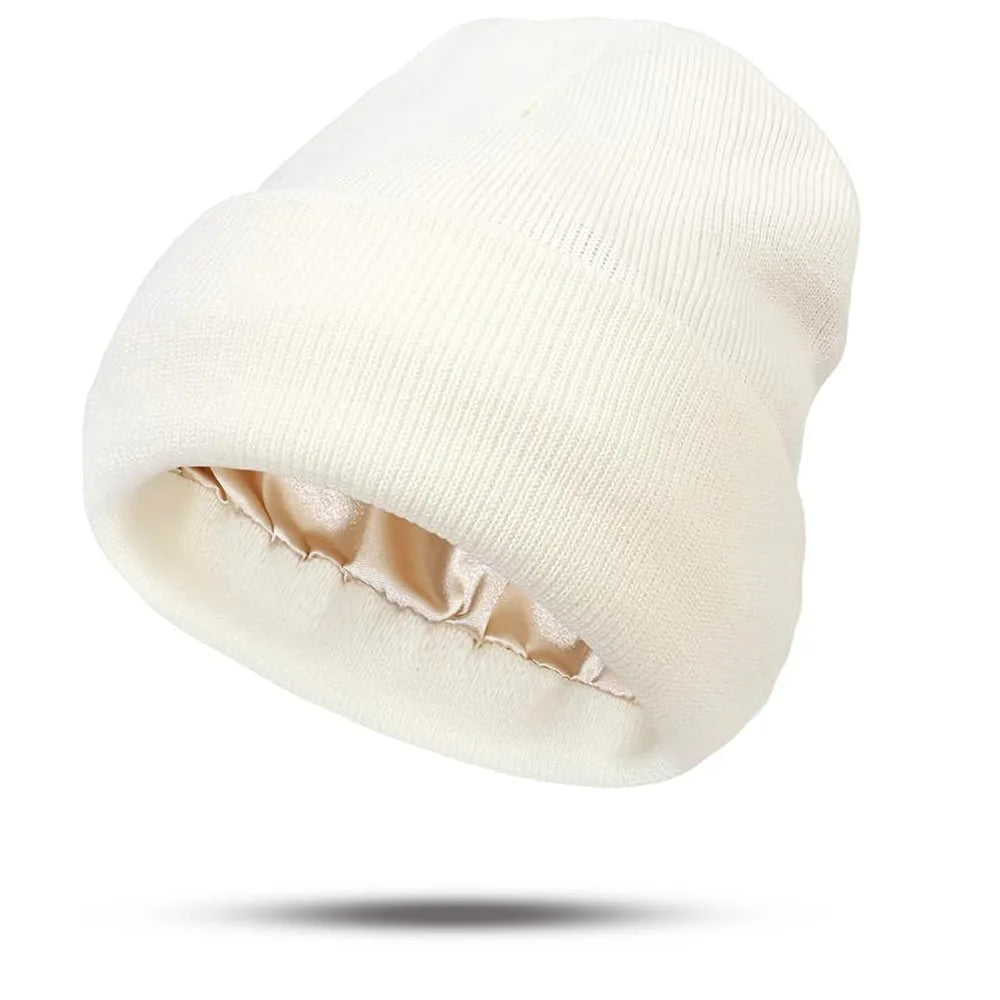 Cream-coloured knitted beanie hat featuring a soft champagne-coloured satin lining.