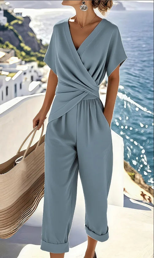 Blue wrap-front jumpsuit with V-neck, short sleeves, cuffed cropped hems, and side pockets.