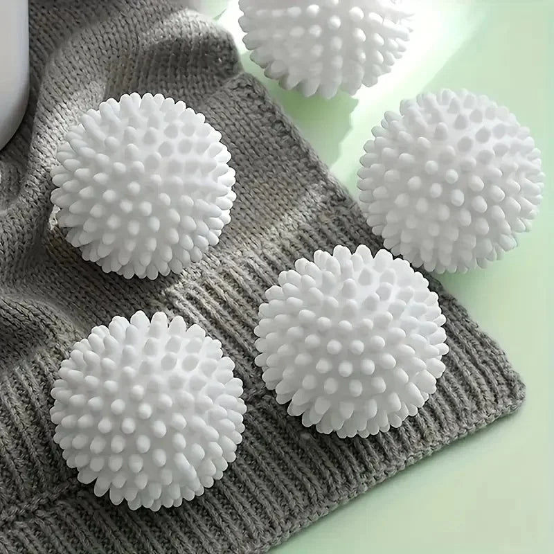 White, spiky laundry balls resting on a folded grey knitted sweater.