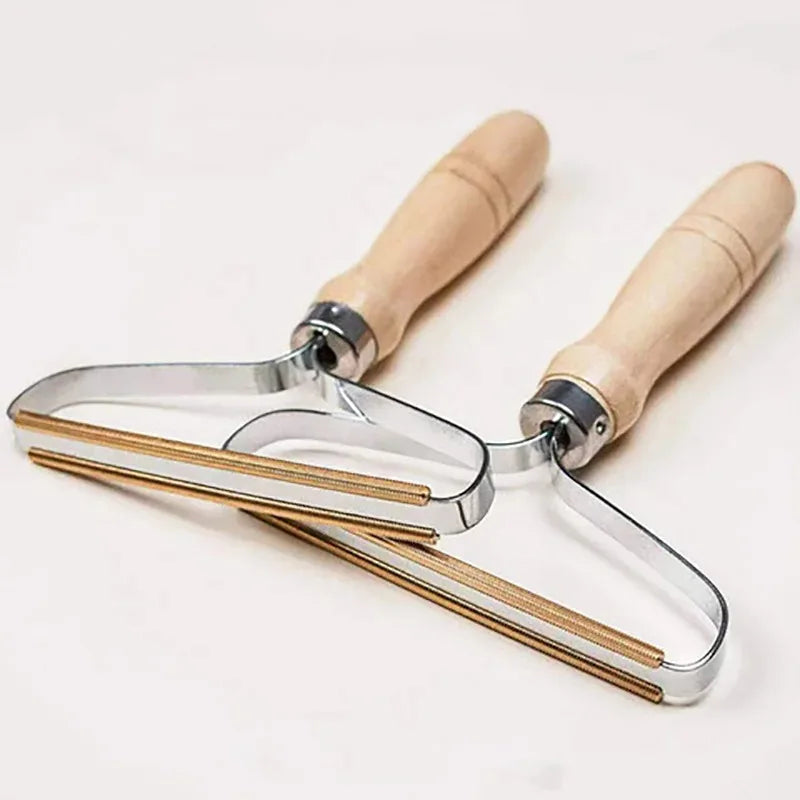Two metal lint removers with copper edges and light wooden handles, angled on a plain white background.
