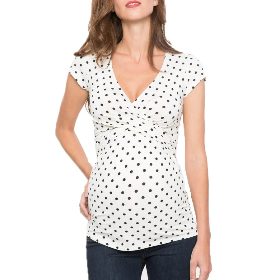 White maternity top with black polka dots, featuring a V-neckline, cap sleeves, and a flattering twist-front design.