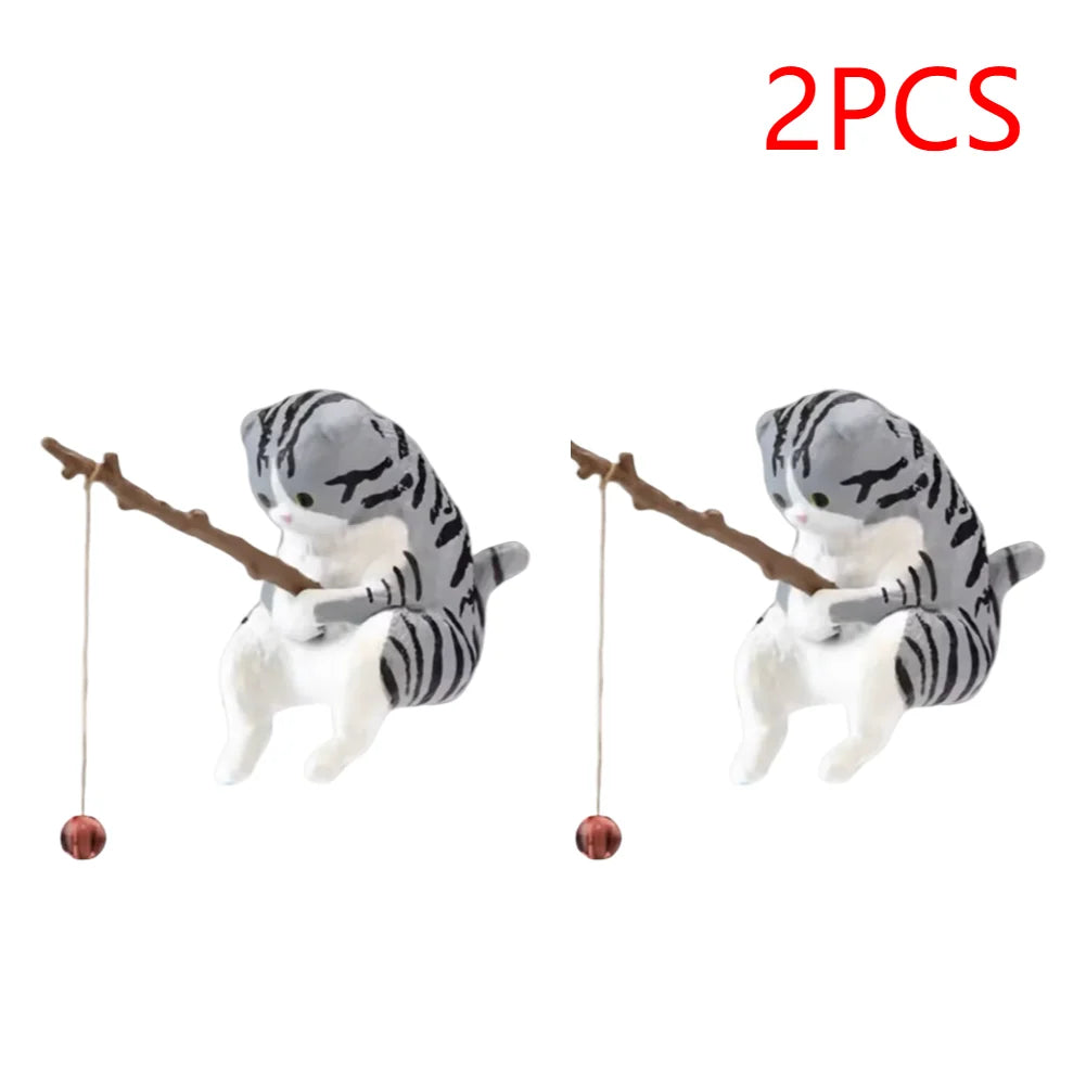 Two grey tabby cat ornaments for an aquarium, each sitting and holding a miniature fishing rod with a tiny lure.