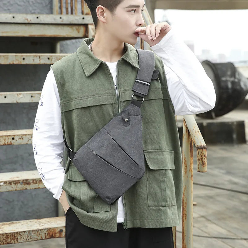 Grey slimline waterproof crossbody chest bag worn by a man in a green utility vest.