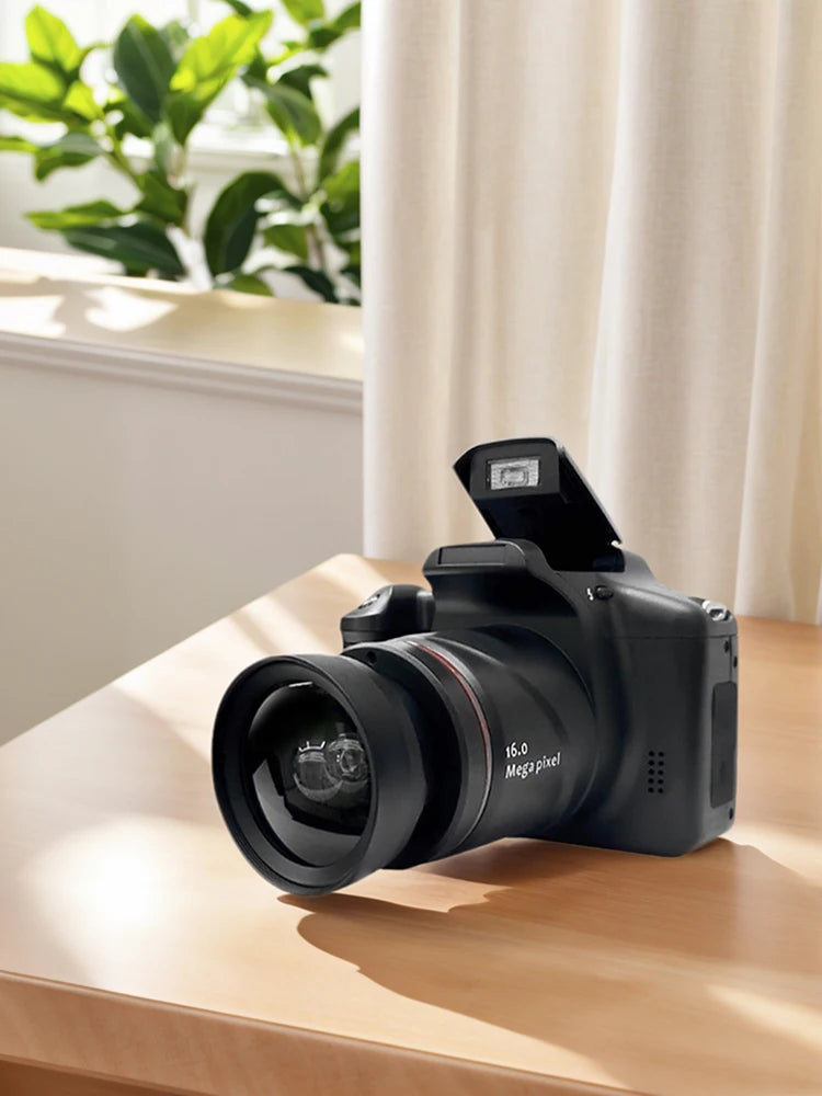 Black digital camera with a 16.0 megapixel lens and pop-up flash resting on a wooden table.