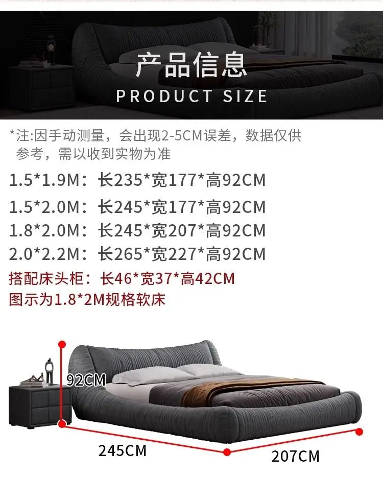 A low-profile, dark grey upholstered bed frame with a curved, textured headboard and matching bedside table.