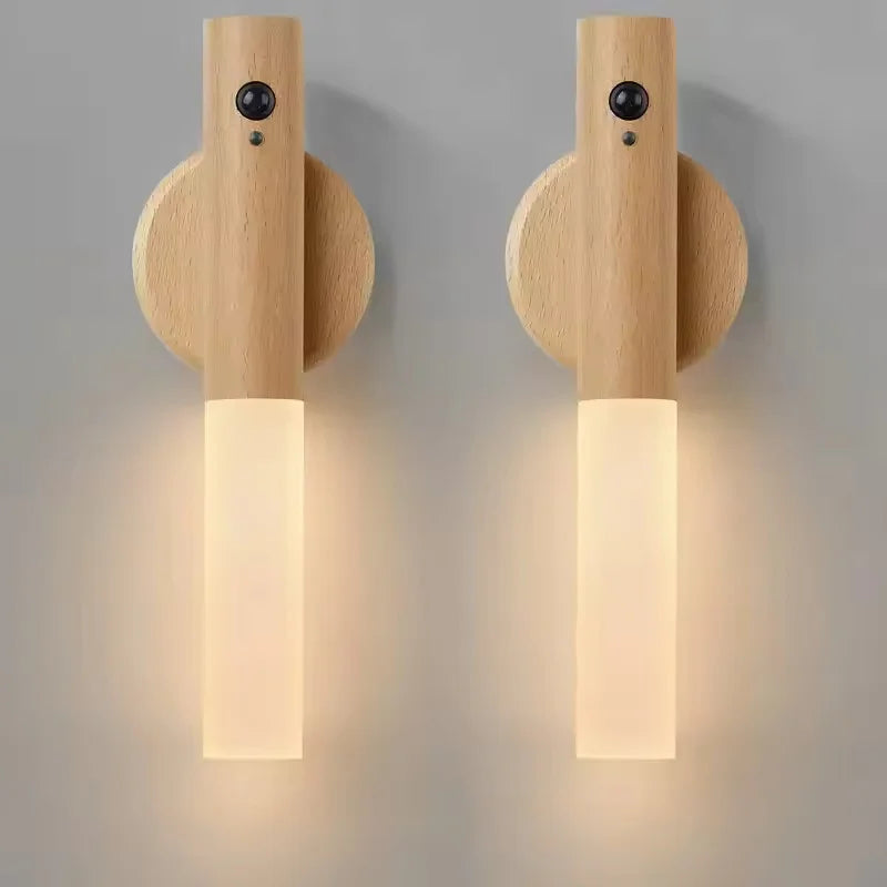 Two sleek, light wood wall-mounted LED night lights with motion sensors and soft, glowing frosted tubes.