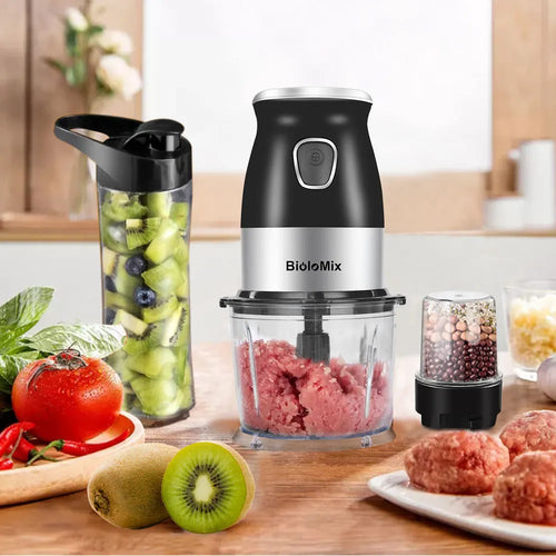 Black and silver electric food processor with glass blending jars, displayed on a wooden table with fresh produce.