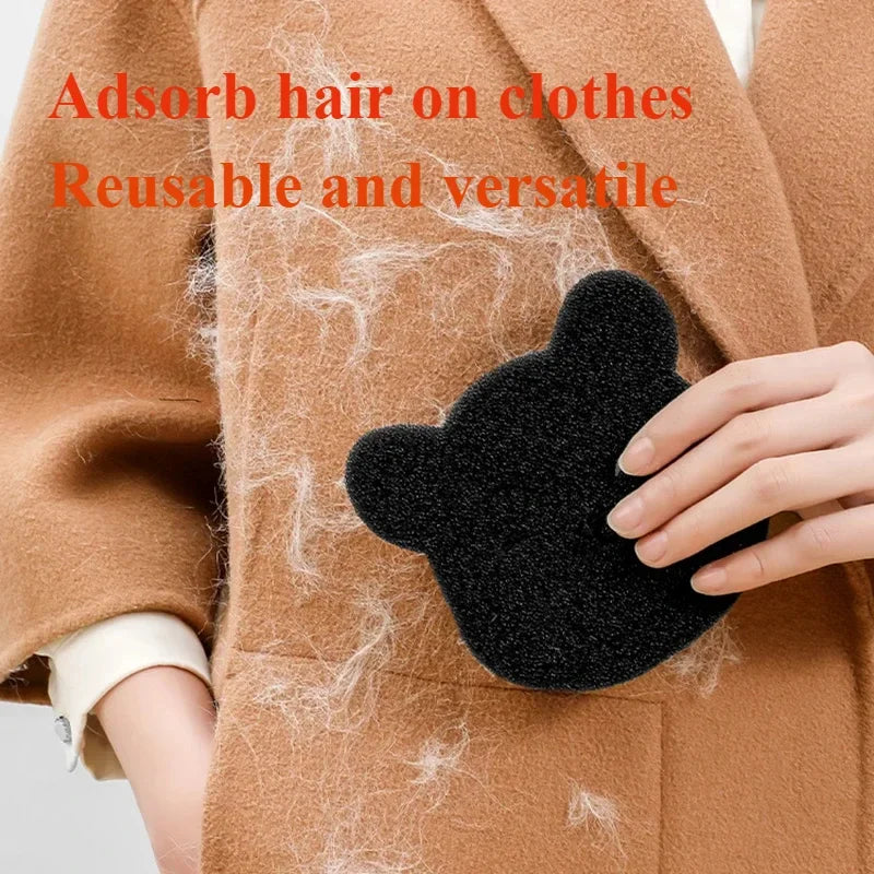 A hand holding a black, bear-shaped reusable sponge cleaning pet hair off a brown wool coat.