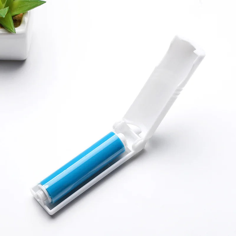 White travel lint roller with a bright blue adhesive sticky sheet, shown with the protective lid open.