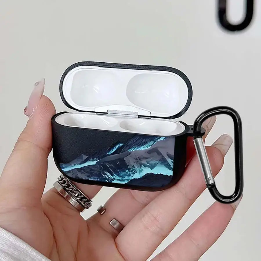 Black AirPod Pro case with a mountain landscape print, made of textured material, including a metal carabiner clip.