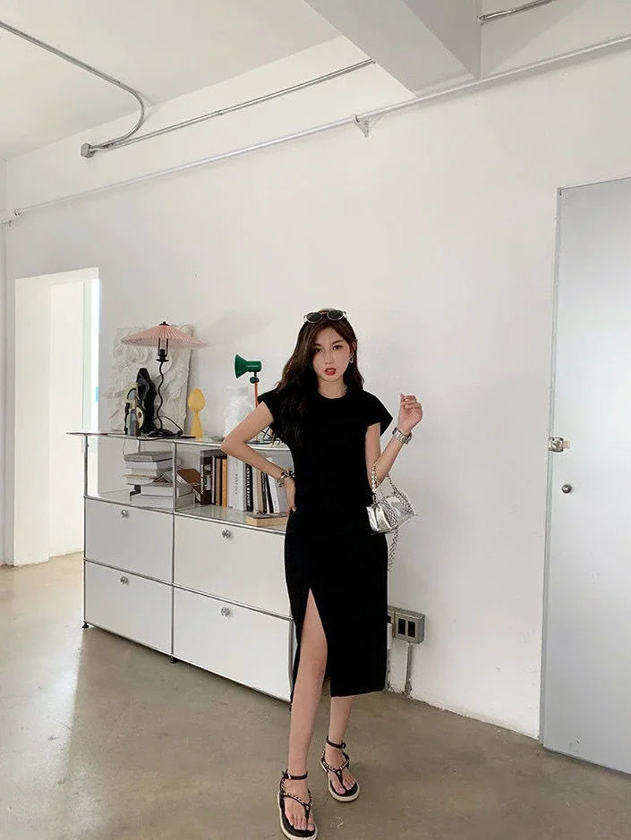 Woman wearing a casual black short-sleeve midi dress with a high side slit, paired with black platform sandals.