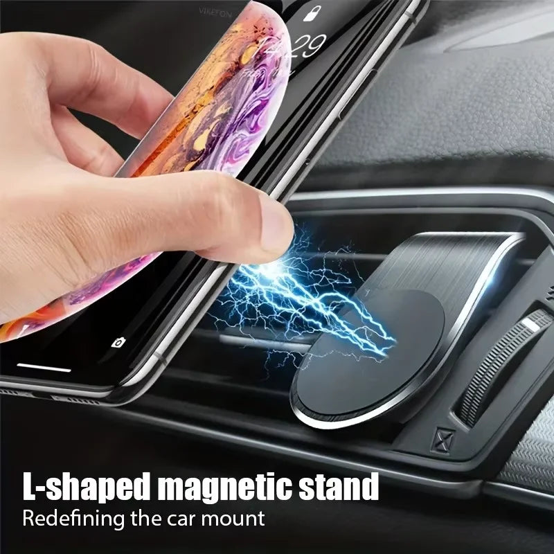 Black L-shaped magnetic car phone mount attached to a vehicle air vent, holding a smartphone.