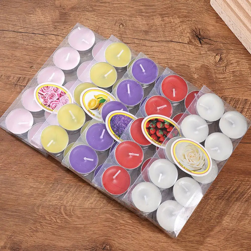 Pack of assorted coloured and scented tea light candles in clear packaging on a wooden surface.
