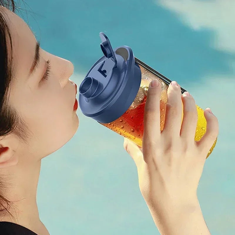 A person drinks from a clear plastic water bottle with a blue flip-top lid against a blue background.