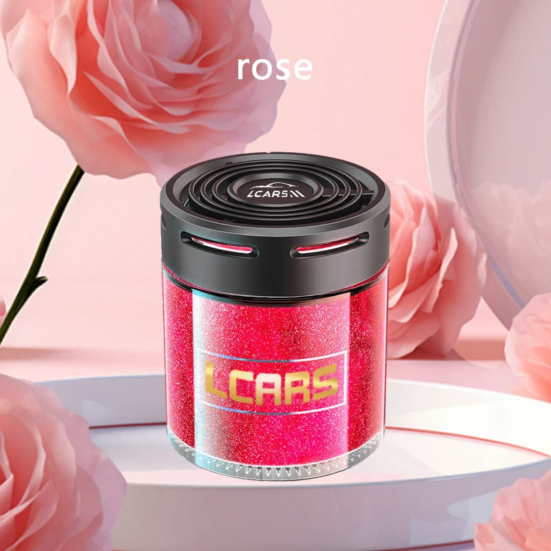 Cylindrical pink glitter car air freshener with a black vented cap, set against a soft pink floral background.