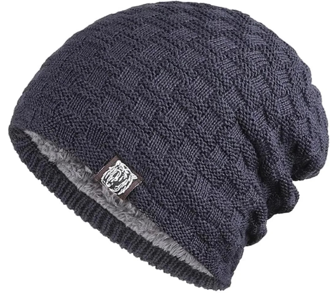 Dark navy chunky-knit unisex beanie with a grey plush lining and a small square logo patch on the ribbed hem.