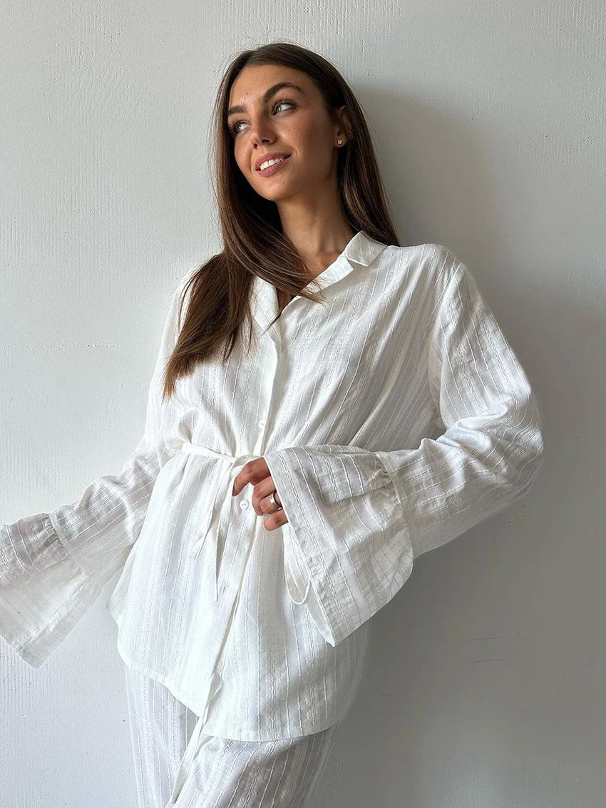 White textured button-up shirt with a collar, tie waist, and flared long sleeves.