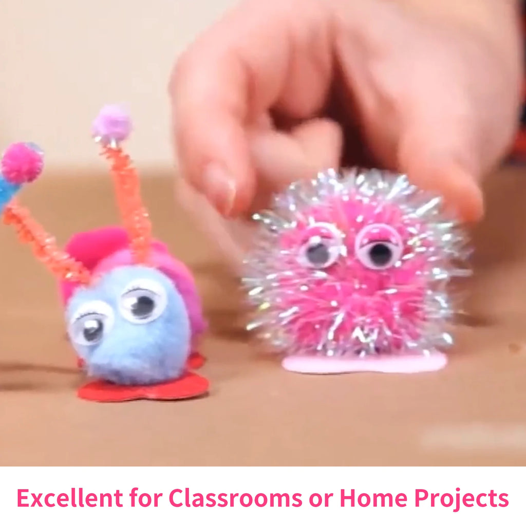 Two DIY fuzzy creatures made from pom-poms, googly eyes, and pipe cleaners, set against a plain brown background.