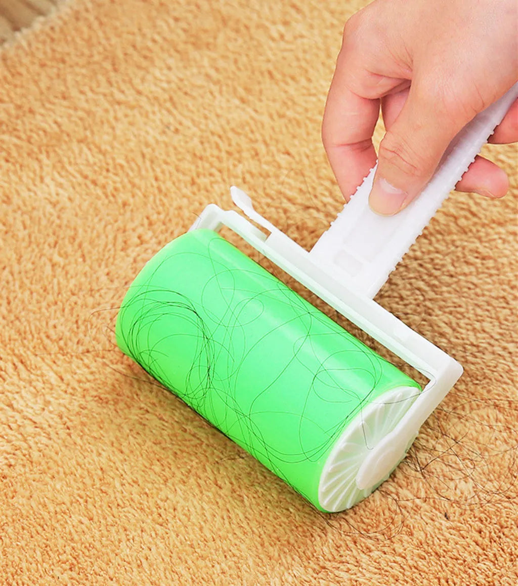 A hand using a bright green sticky lint roller to remove dark hair from a textured tan carpet.