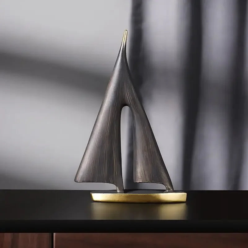 Minimalist resin sailboat ornament with a dark grey textured finish and a contrasting gold-coloured base.
