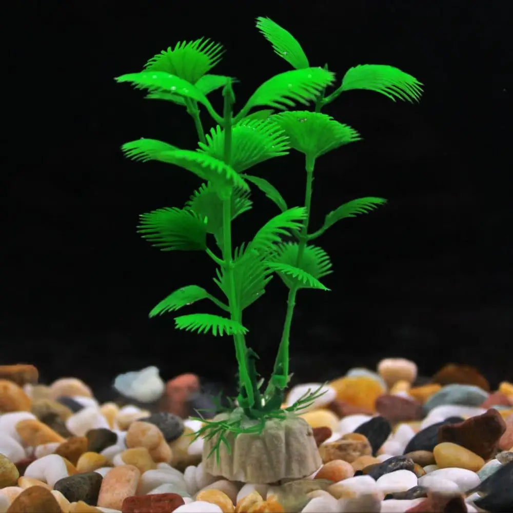 Artificial bright green aquarium plant with fan-shaped leaves, anchored in a base on colorful gravel.