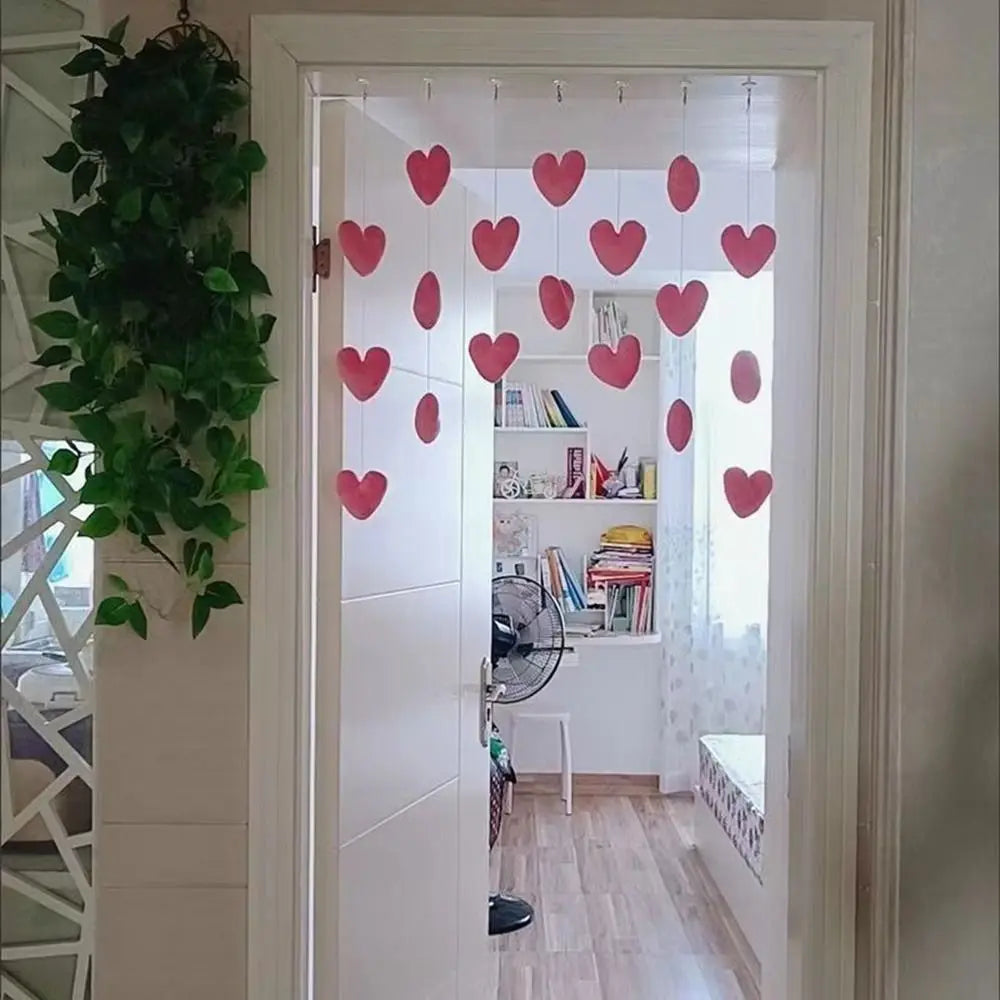 Rows of red heart-shaped decorations hanging from strings in a doorway, creating a romantic bedroom feature.