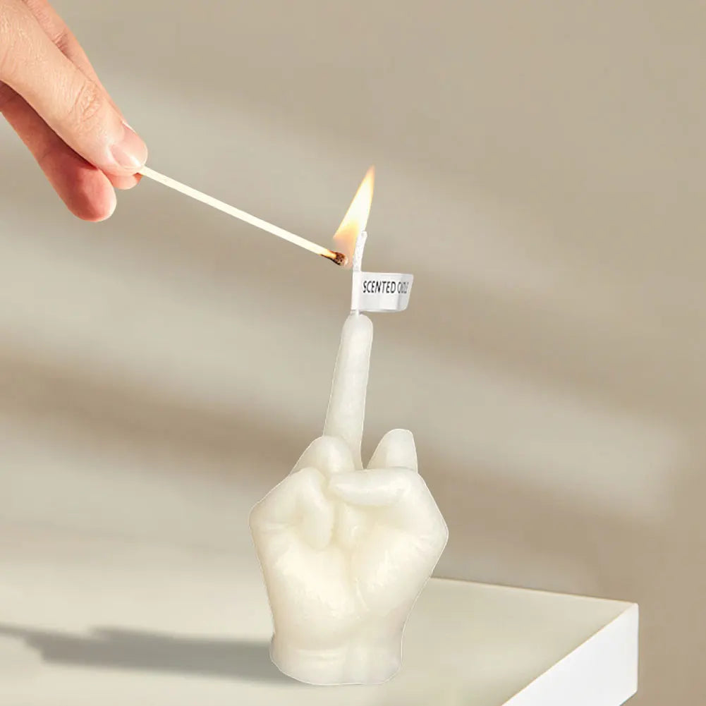 White candle shaped like a hand giving the middle finger, being lit with a match.