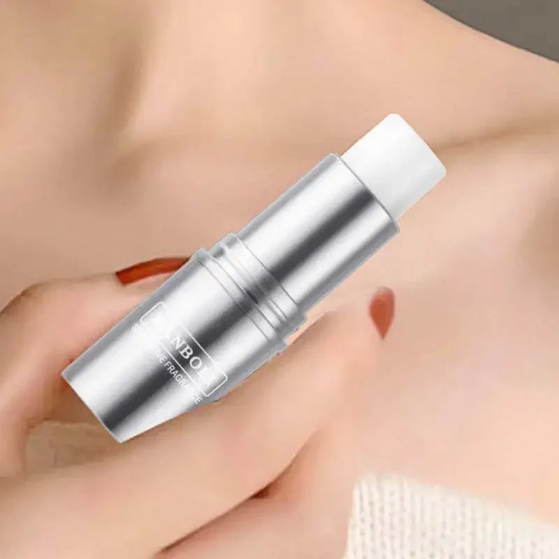 Silver cylindrical roller ball perfume tube held in hand against skin.