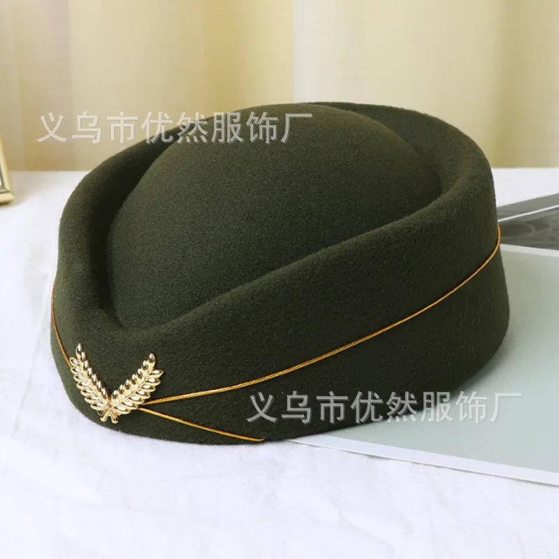 Dark olive green felt pillbox hat, vintage stewardess style, featuring a gold trim detail and a decorative leaf emblem.