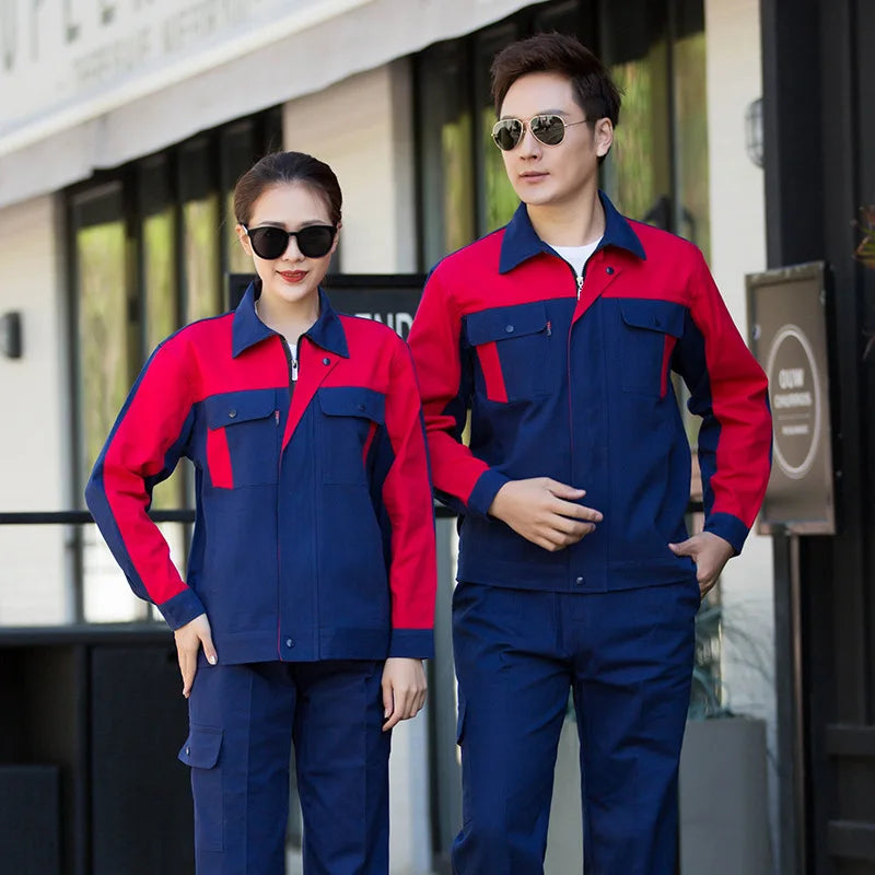 A man and woman wearing red and blue collared work jackets and matching trousers with pockets.