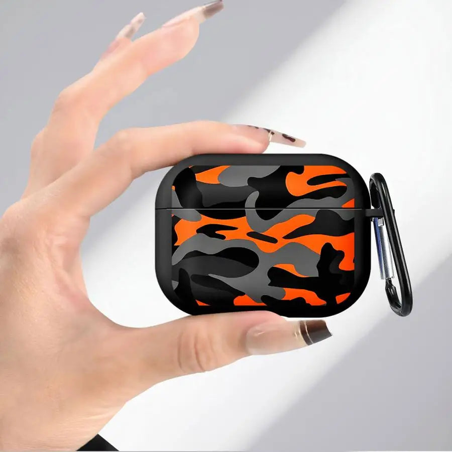 Black and orange camouflage silicone protective case for AirPods Pro, held in hand with a black carabiner clip.