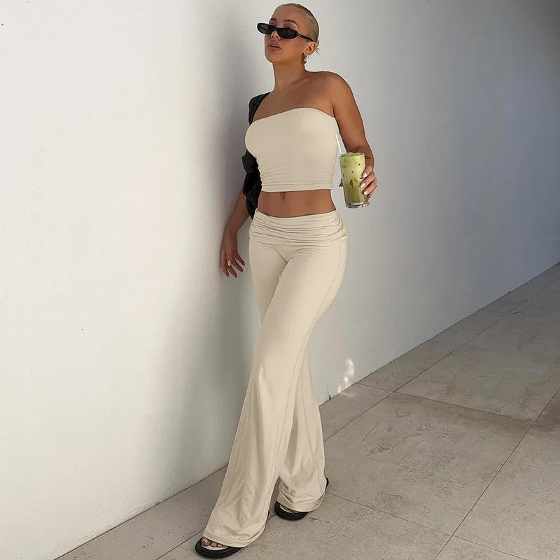 A woman wearing a cream-coloured strapless bandeau crop top and matching flared trousers with a low-rise waist.