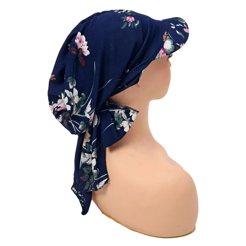 Navy blue headscarf hat with a floral print, featuring a curved brim and a soft tie-back style on a mannequin.
