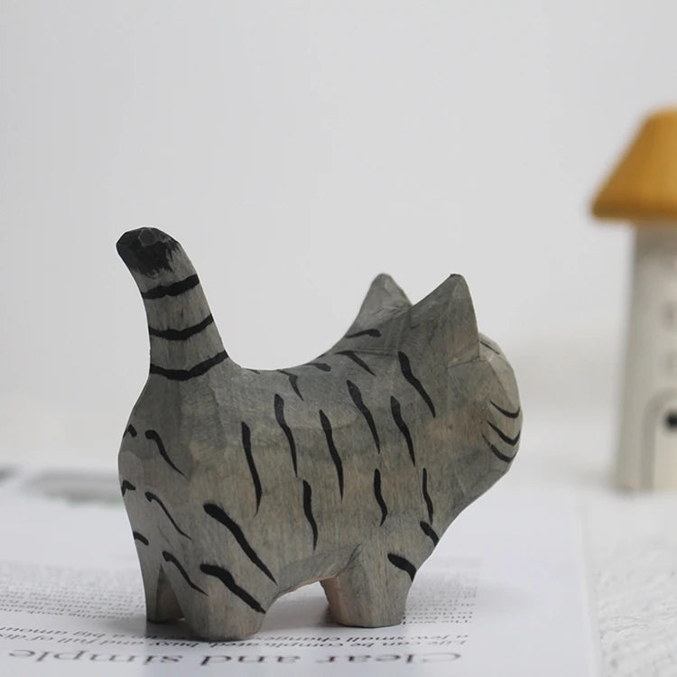 Hand-carved grey wooden cat figurine with black tiger-style stripes and an upright tail.