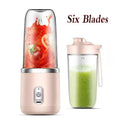 Portable personal blender with a blush pink base, six blades, and a clear blending cup filled with smoothie ingredients.