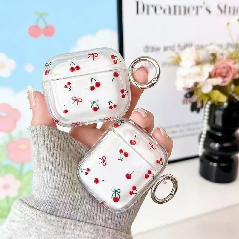 Clear plastic AirPods case featuring a red cherry and bow print, complete with a silver keyring attachment.