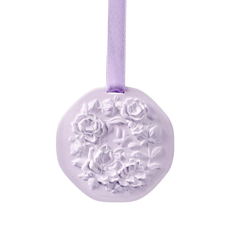 Light purple solid wax fragrance tablet with embossed floral design, hanging by a matching ribbon.