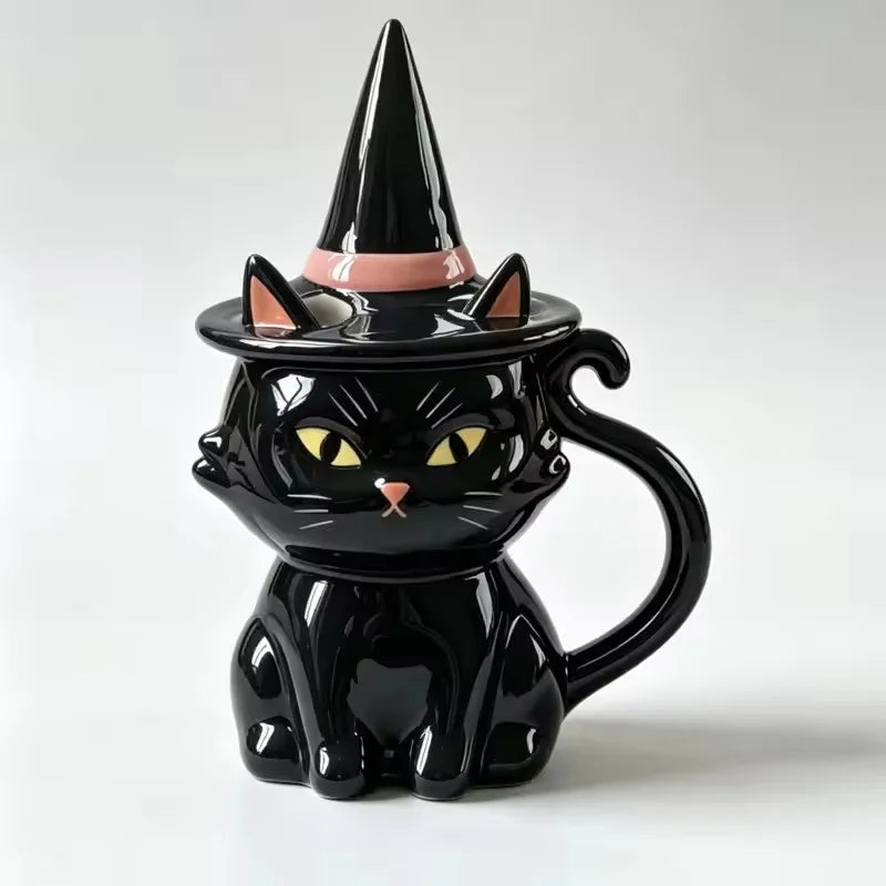 Black ceramic cat mug with yellow eyes, pink nose, curved tail handle, and a matching witch hat lid.