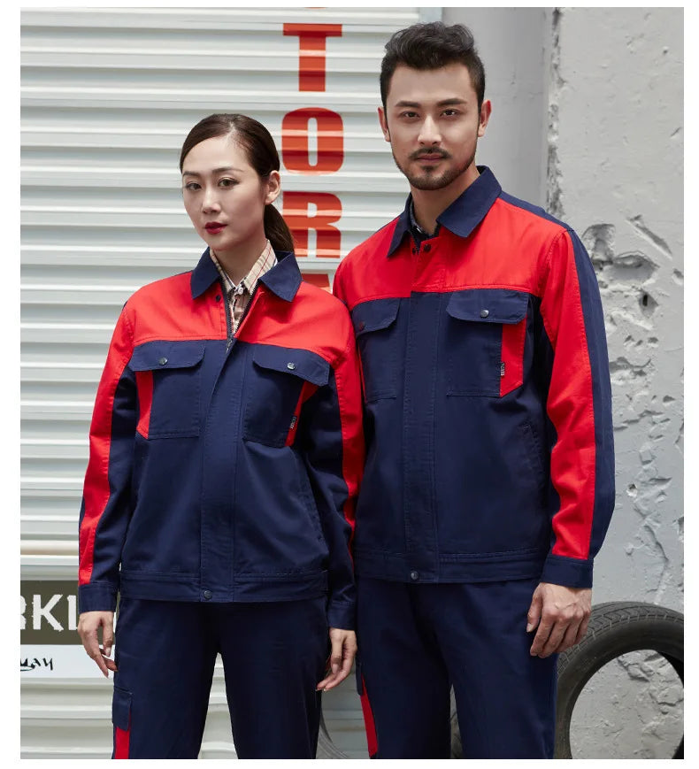 Man and woman wearing navy and red color-blocked cotton-blend work jackets with buttoned chest pockets and collars.