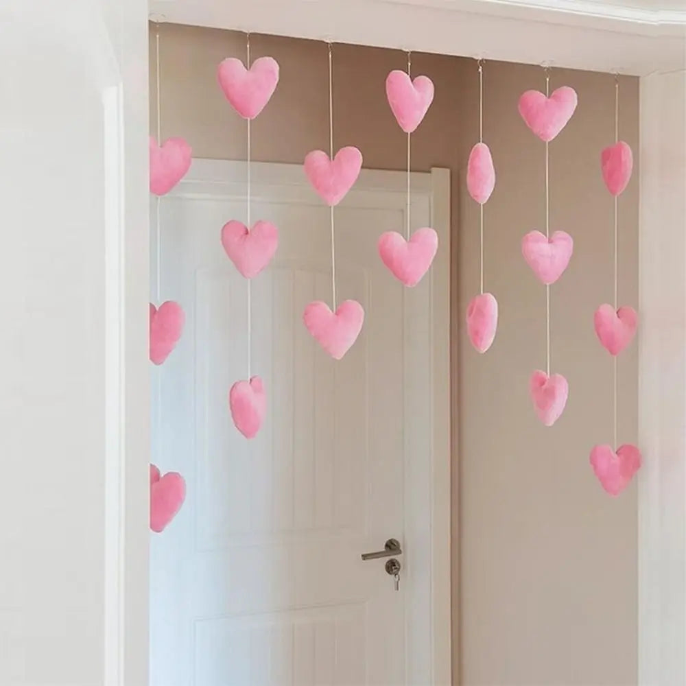 Hanging strings of soft, plush baby-pink hearts for bedroom decoration, suspended in a doorway.